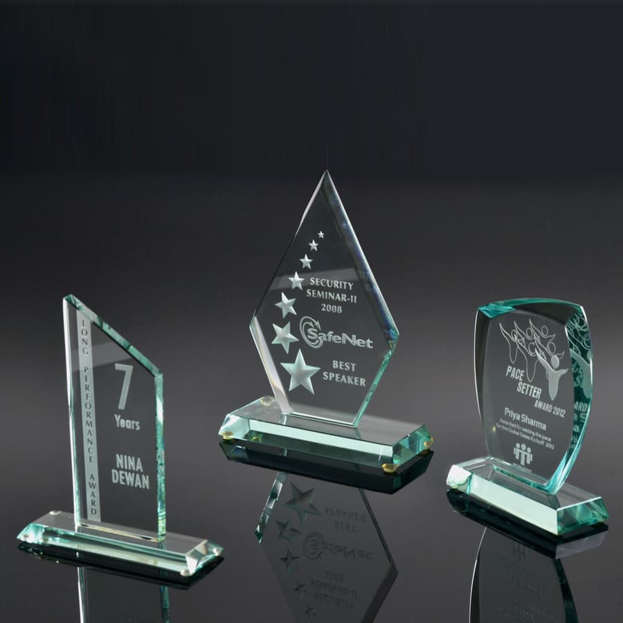 Three green glass awards with unique designs on them