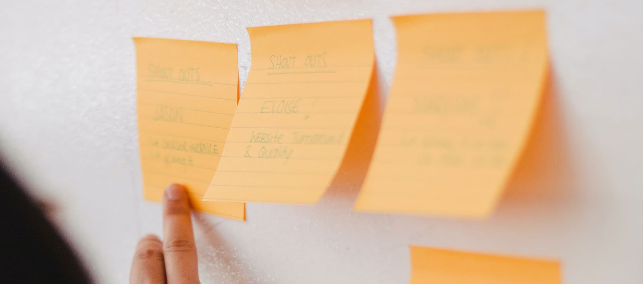 Person pointing to wall covered in sticky notes